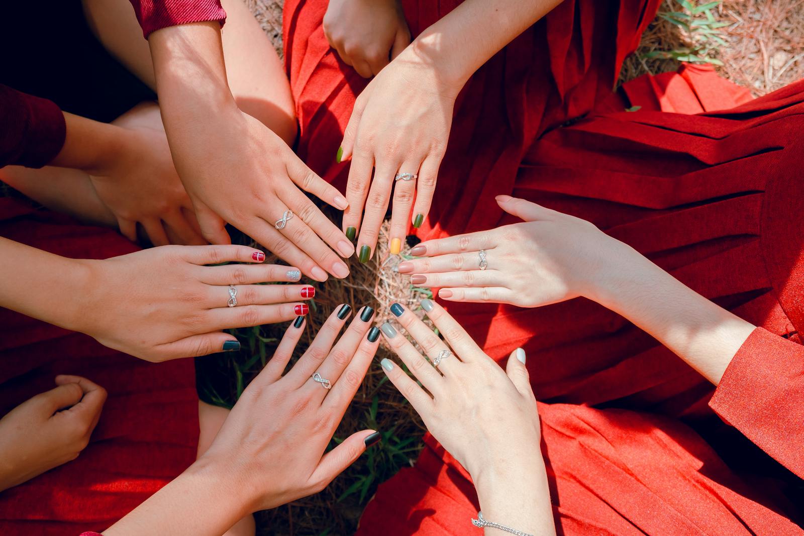 A vibrant top view of women showcasing painted nails and rings, emphasizing friendship and togetherness.