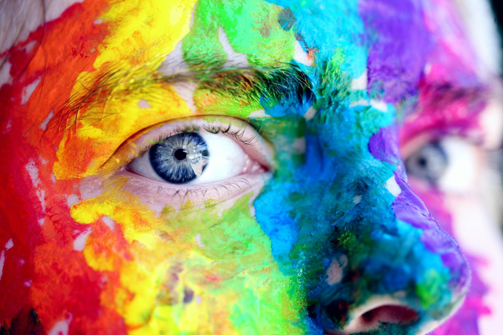 Close-up of a person with colorful rainbow face paint, symbolizing LGBT pride and expression.