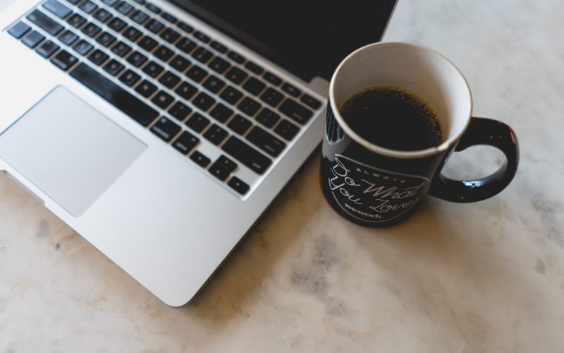 coffee in mug beside MacBook Pro