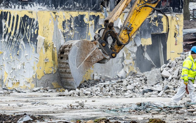 a man in a yellow jacket and a yellow bulldozer